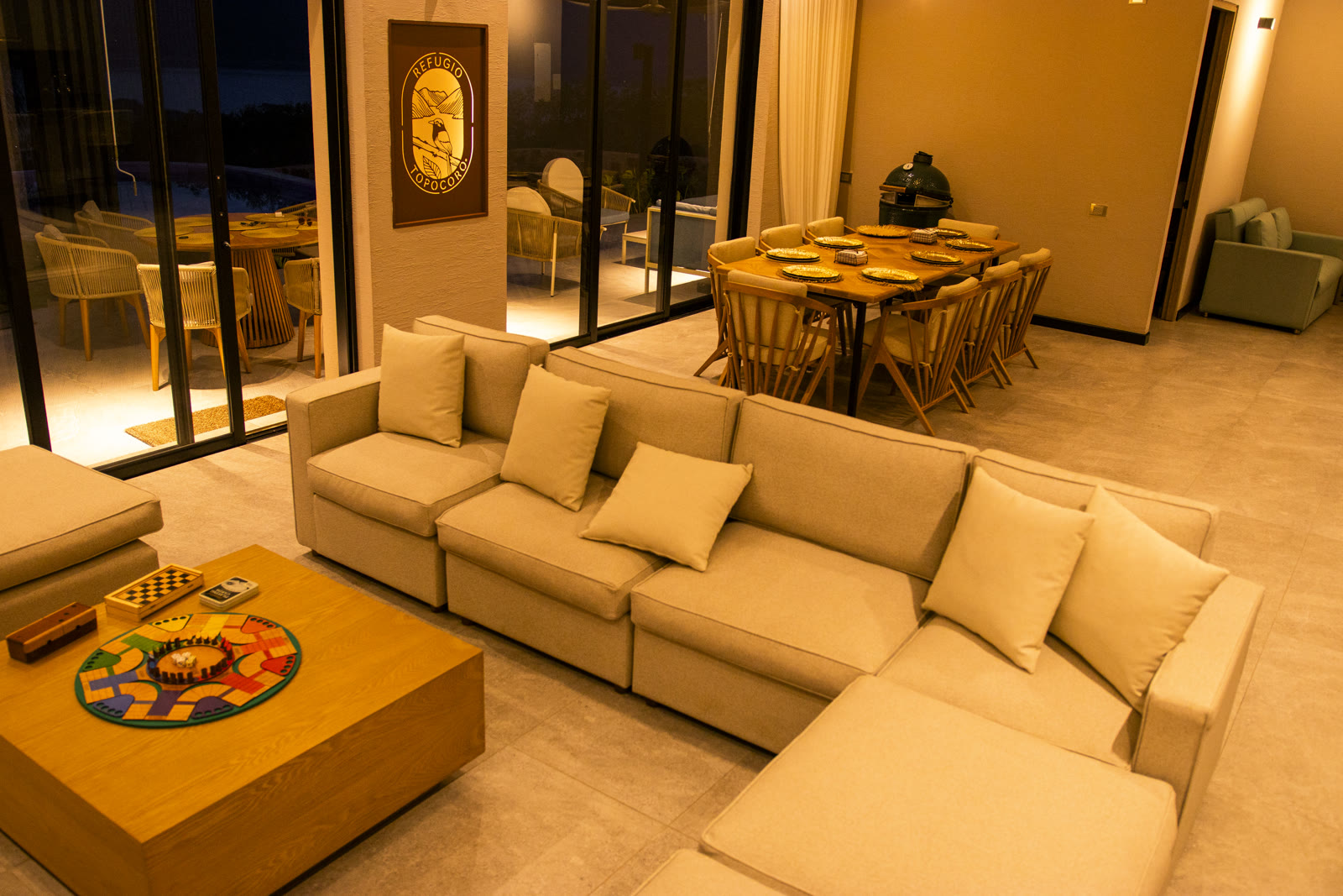 Sala y comedor de la casa modelo de Altos de Yariguíes de noche, con sofá, mesa servida y vista a la terraza