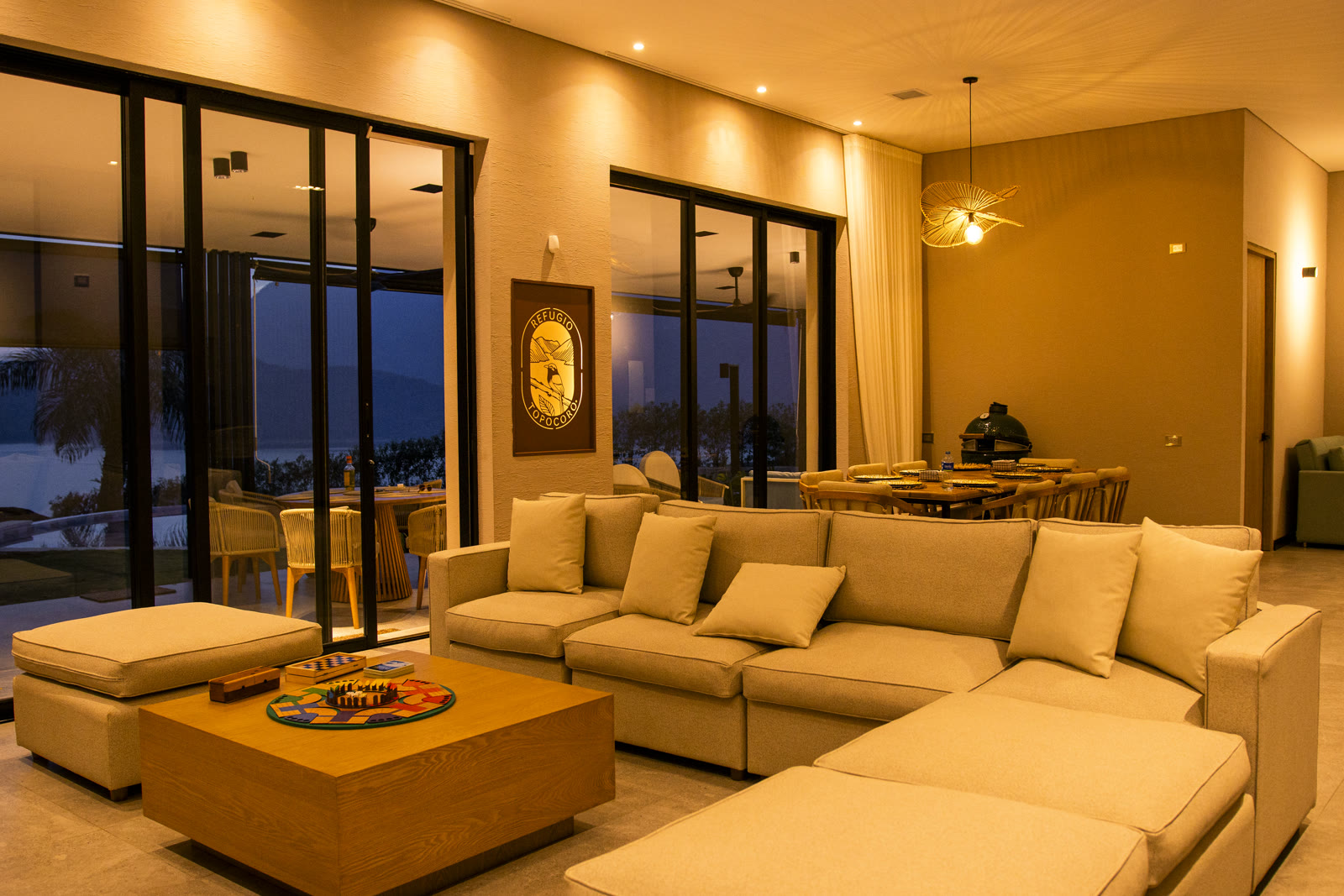Living room of the Altos de Yariguíes model home at dusk, with a view of the Topocoro Reservoir through the windows