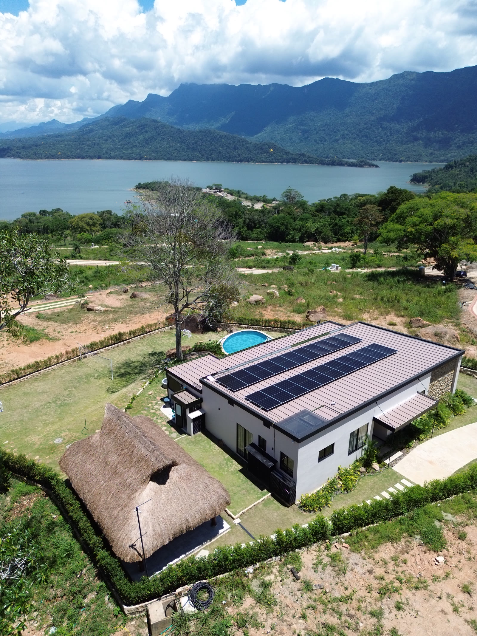 Aerial view of a house with solar panels and a pool facing the Topocoro Reservoir