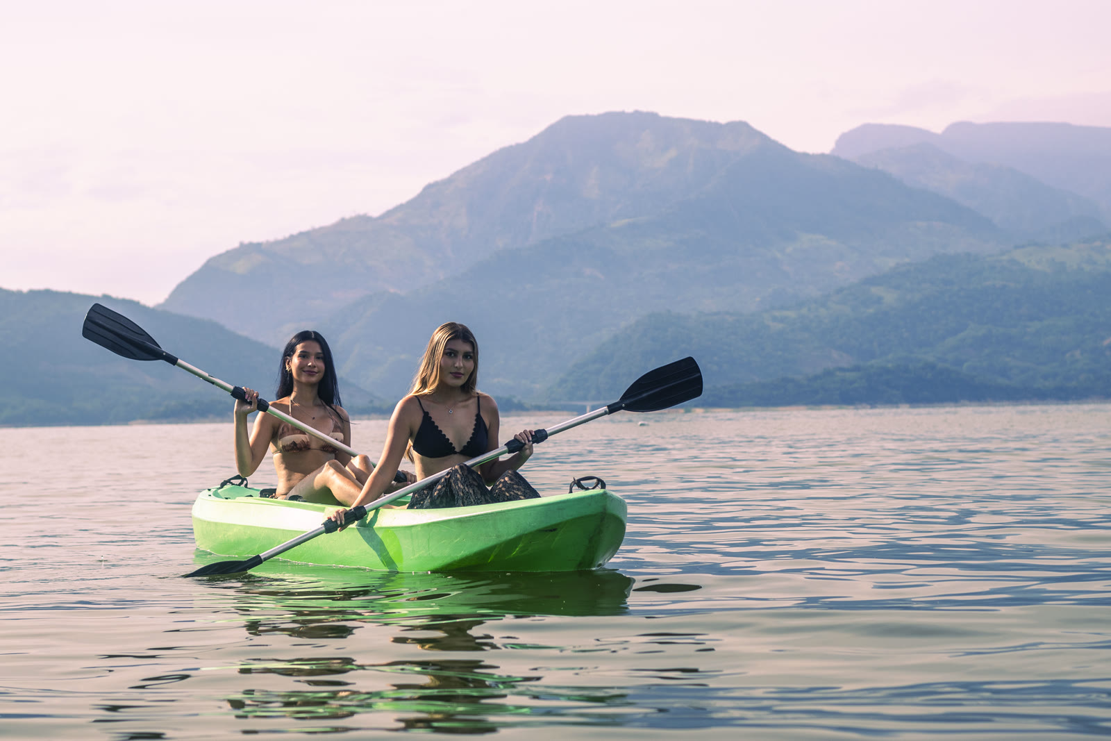Dos amigas remando en kayak sobre el Embalse de Topocoro, con montañas de fondo